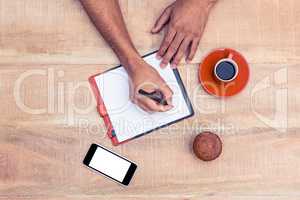 Man writing on diary at table