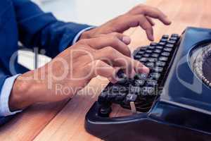 Businessman using typewriter at wooden desk
