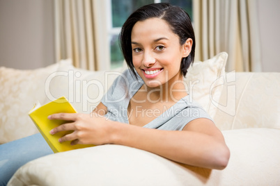 Smiling brunette reading book