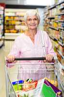 Smiling senior woman pushing trolley