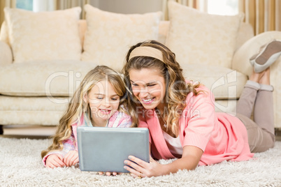 Happy mom and daughter lying on the floor