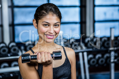 Smiling fit woman doing dumbbells exercise