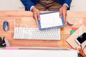 Creative businessman holding digital tablet while sitting at des