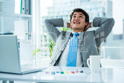 Relaxing asian businessman at his desk
