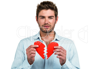 Sad man holding heart halves