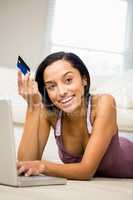 Smiling brunette using laptop and holding credit card