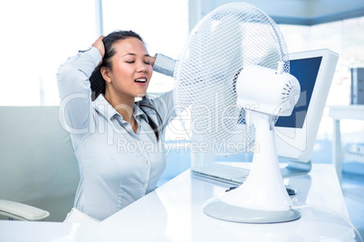 Businesswoman sitting in front of fan