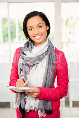 Smiling brunette writing on notepad