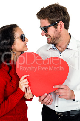 Smiling couple with sunglasses holding paper heart