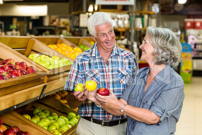 Smiling senior couple holding apples