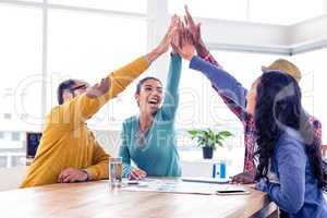 Cheerful business team doing high five in creative office