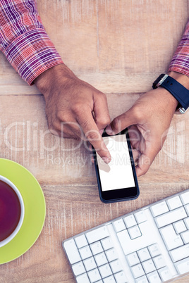 Person using smart phone with coffee and keyboard on desk