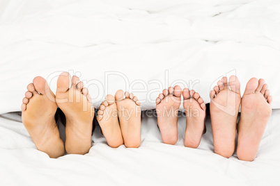 Parents and kids feet at the end of the bed