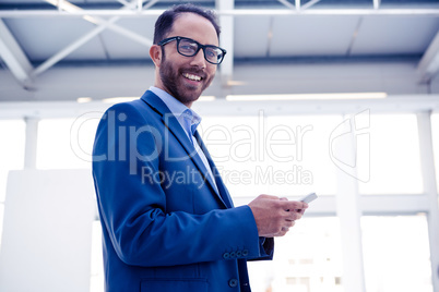 Portrait of happy businessman holding smartphone in office