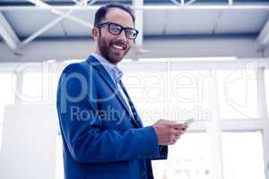 Portrait of happy businessman holding smartphone in office