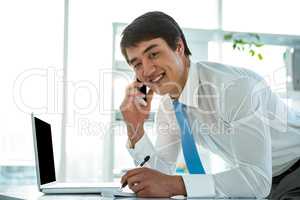 Smiling asian businessman writing notes