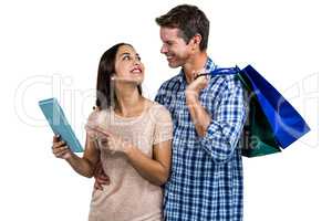 Couple with shopping bags using digital tablet