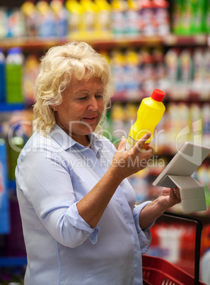 Senior woman with pad reading the detergent label