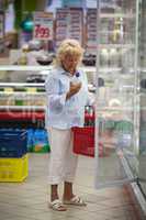 Woman taking milk from the fridge in supermarket