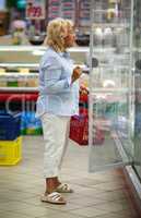 Woman choosing products in open fridge with dairy