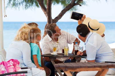 Family selfie with tablet PC in outdoor cafe on resort