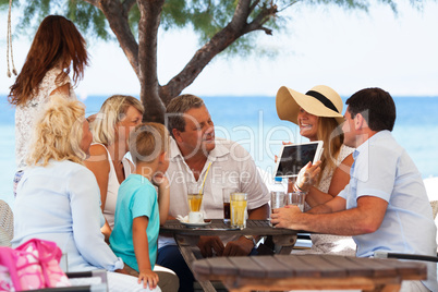 Family looking at photo on touch pad in outdoor cafe