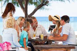 Family looking at photo on touch pad in outdoor cafe