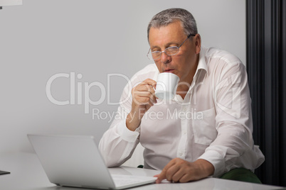 Businessman drinking coffee while working in office