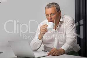 Businessman drinking coffee while working in office
