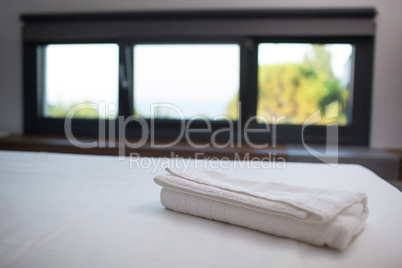 Clean white towel on the bed in hotel room