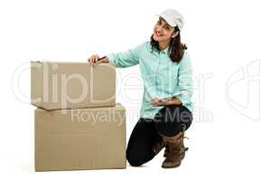 Delivery woman with clipboard kneeling by box