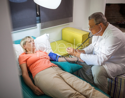 Doctor measuring blood pressure of woman at home