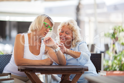 Mature women using smart watch in street cafe