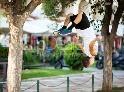 Young sportsman doing front flip in the street