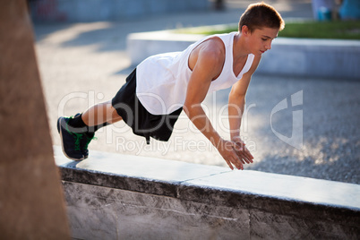 Teenager performing push-ups outdoor in city