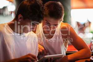 Young men using tablet computer in cafe