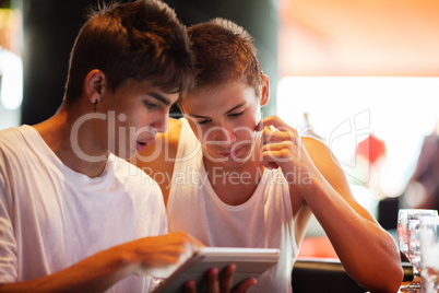 Young men searching on the internet with pad in cafe