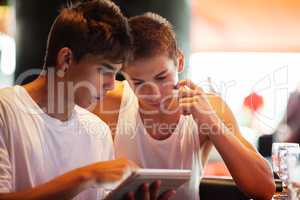 Young men searching on the internet with pad in cafe