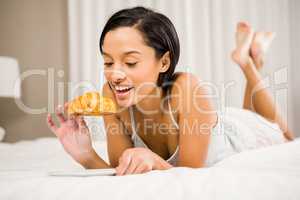 Smiling brunette eating croissant