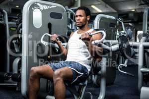 Serious muscular man using exercise machine