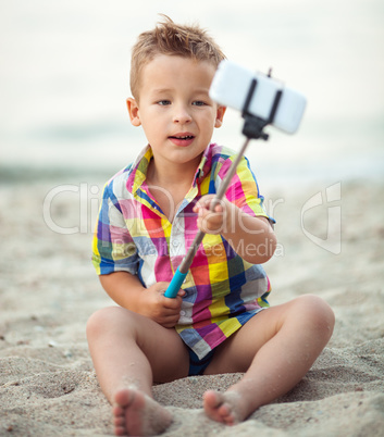 Child with phone and selfie stick on the beach