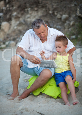 Grandfather and grandchild using pad on the beach