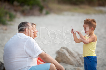 Boy taking phone photo of grandparents outdoor