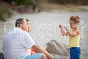 Boy taking phone photo of grandparents outdoor