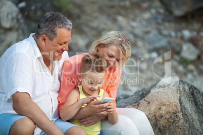 Happy boy with cell phone and grandparents outdoor