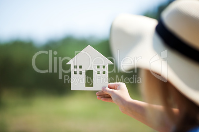 Woman holding house model in the countryside