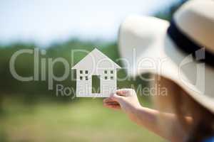 Woman holding house model in the countryside