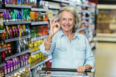 Smiling senior woman doing ok sign with hand