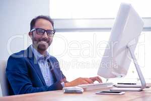 Portrait of happy businessman working on computer in office
