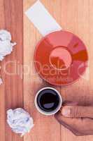Cropped hand holding coffee cup by crumbled paper